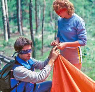 alumni blindfolded setting up a tent